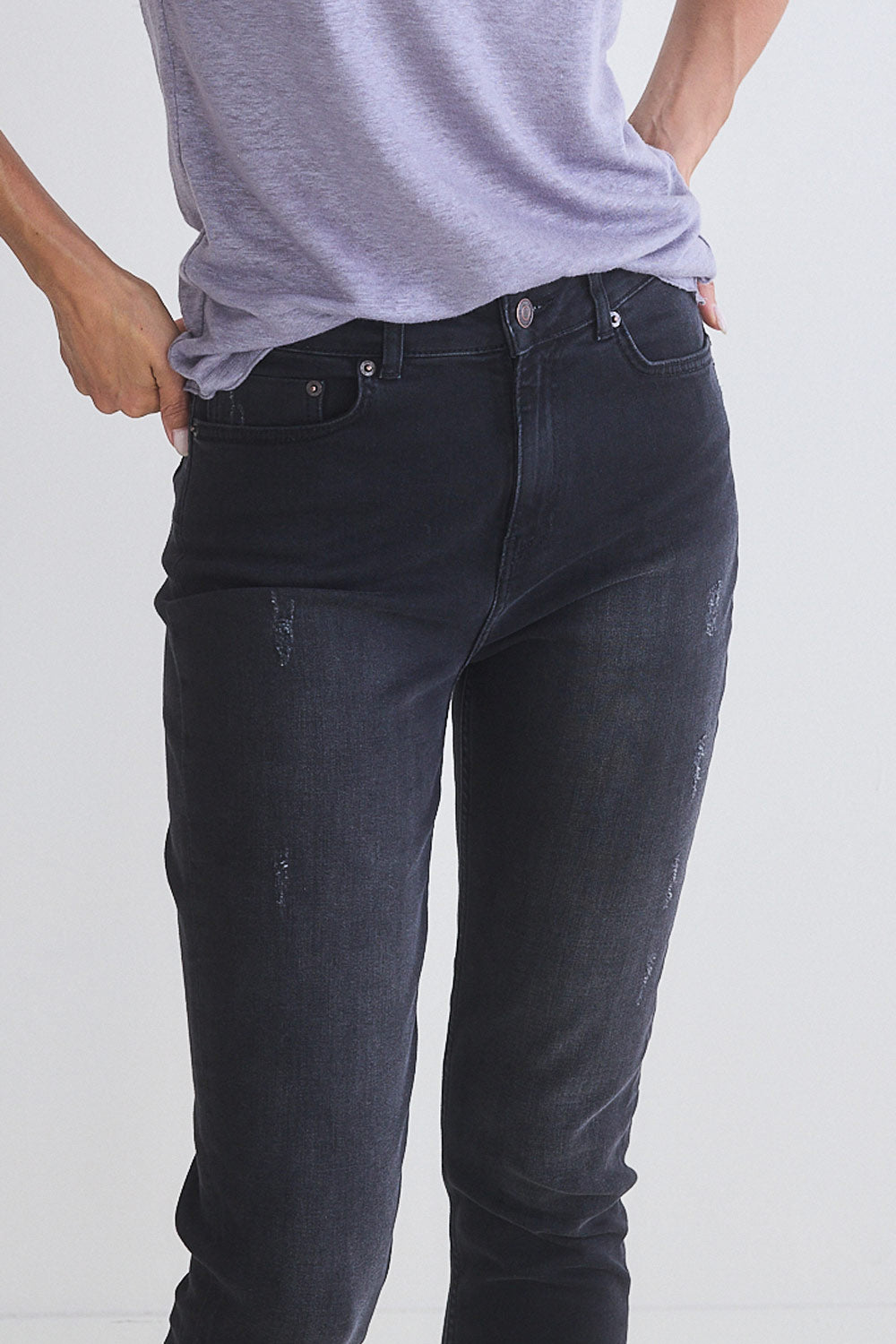 Dark jeans close-up with front button, pocket, and subtle wash effect