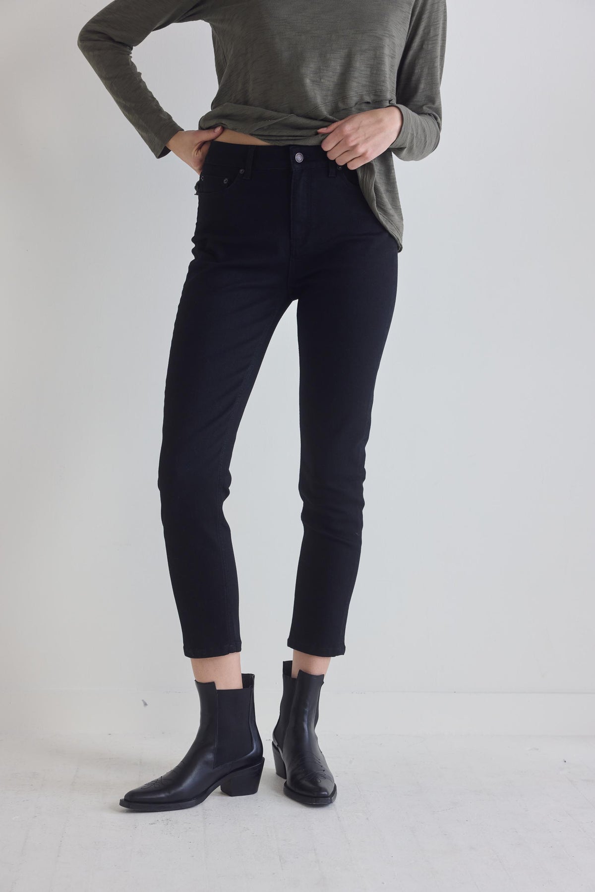 Black fitted jeans with tapered ankle hem and front pockets, worn with black boots.