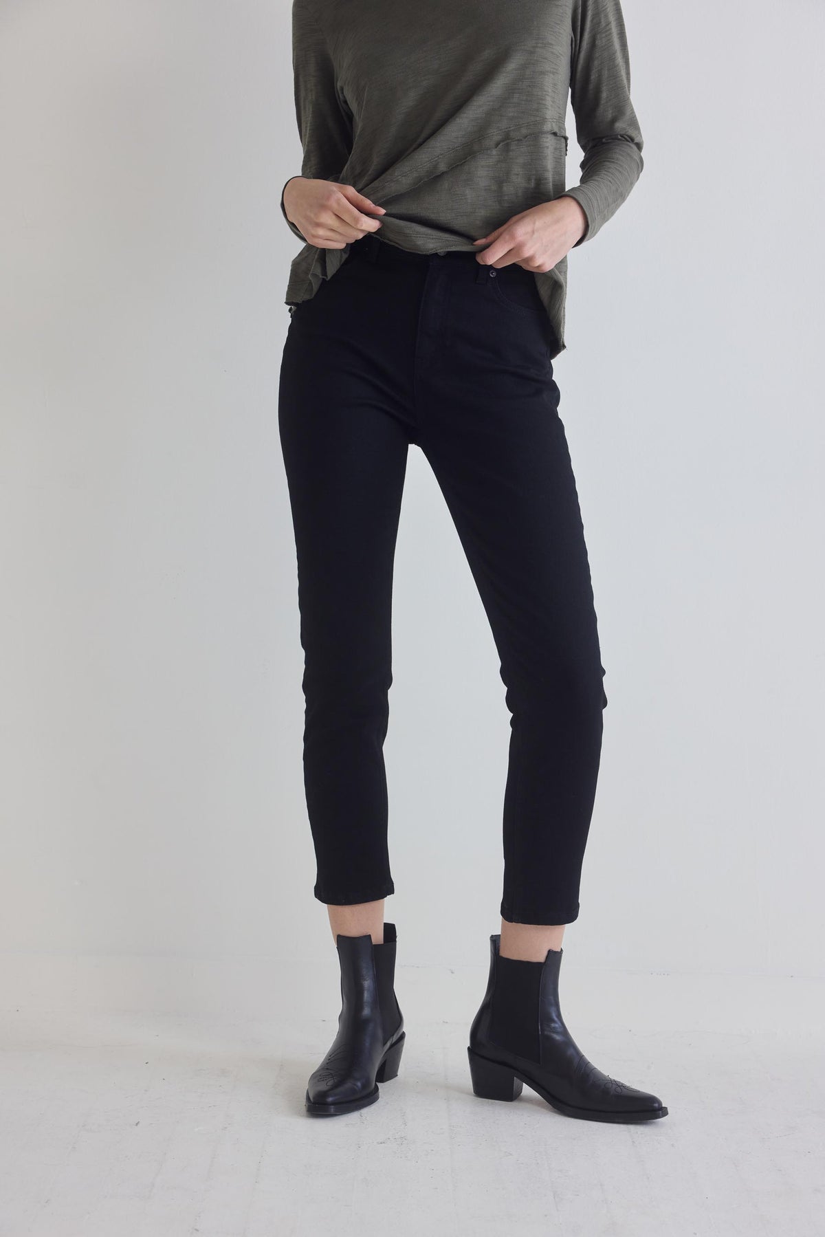 Black fitted jeans with straight seams and ankle hem, full front view with boots.