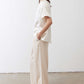 Oatmeal linen wide-leg trousers side view with tied waist and wide, relaxed hem
