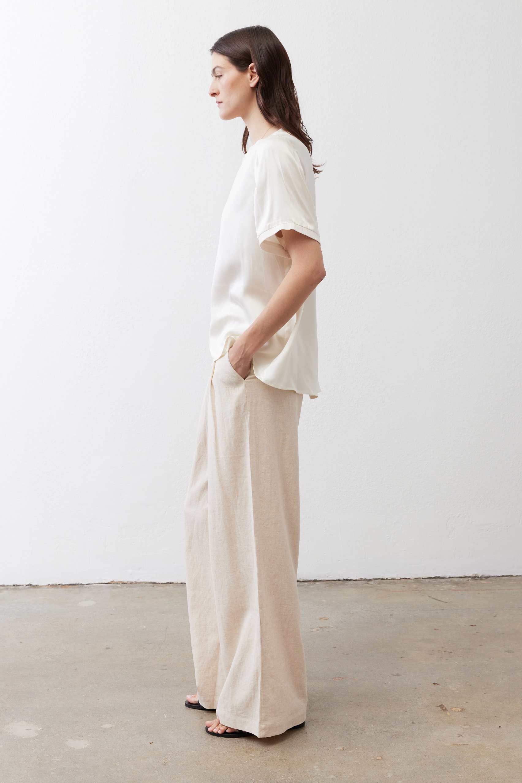 Oatmeal linen wide-leg trousers side view with tied waist and wide, relaxed hem