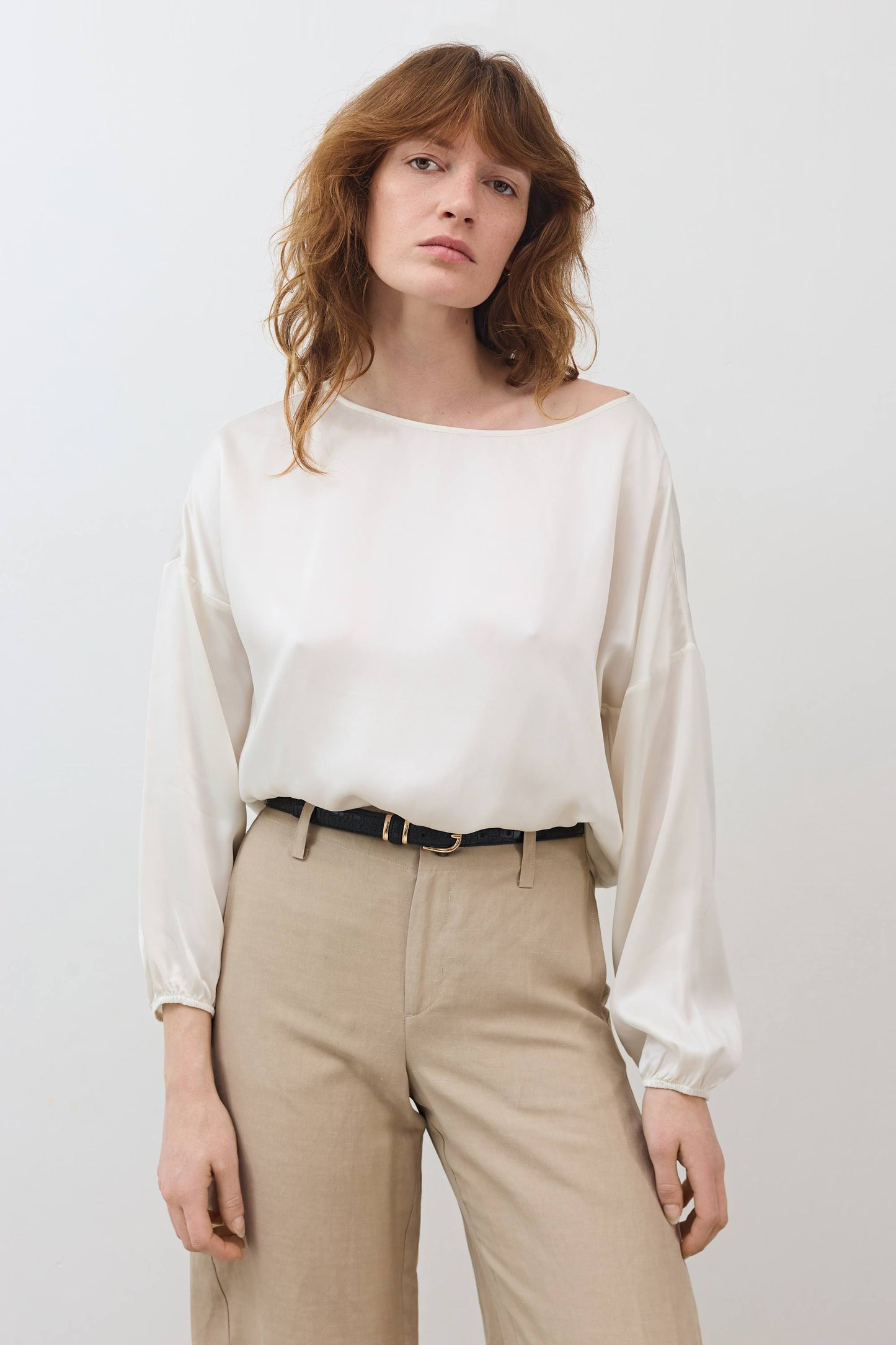 Ivory silk blouse with scoop neck, long puff sleeves, and cinched hem