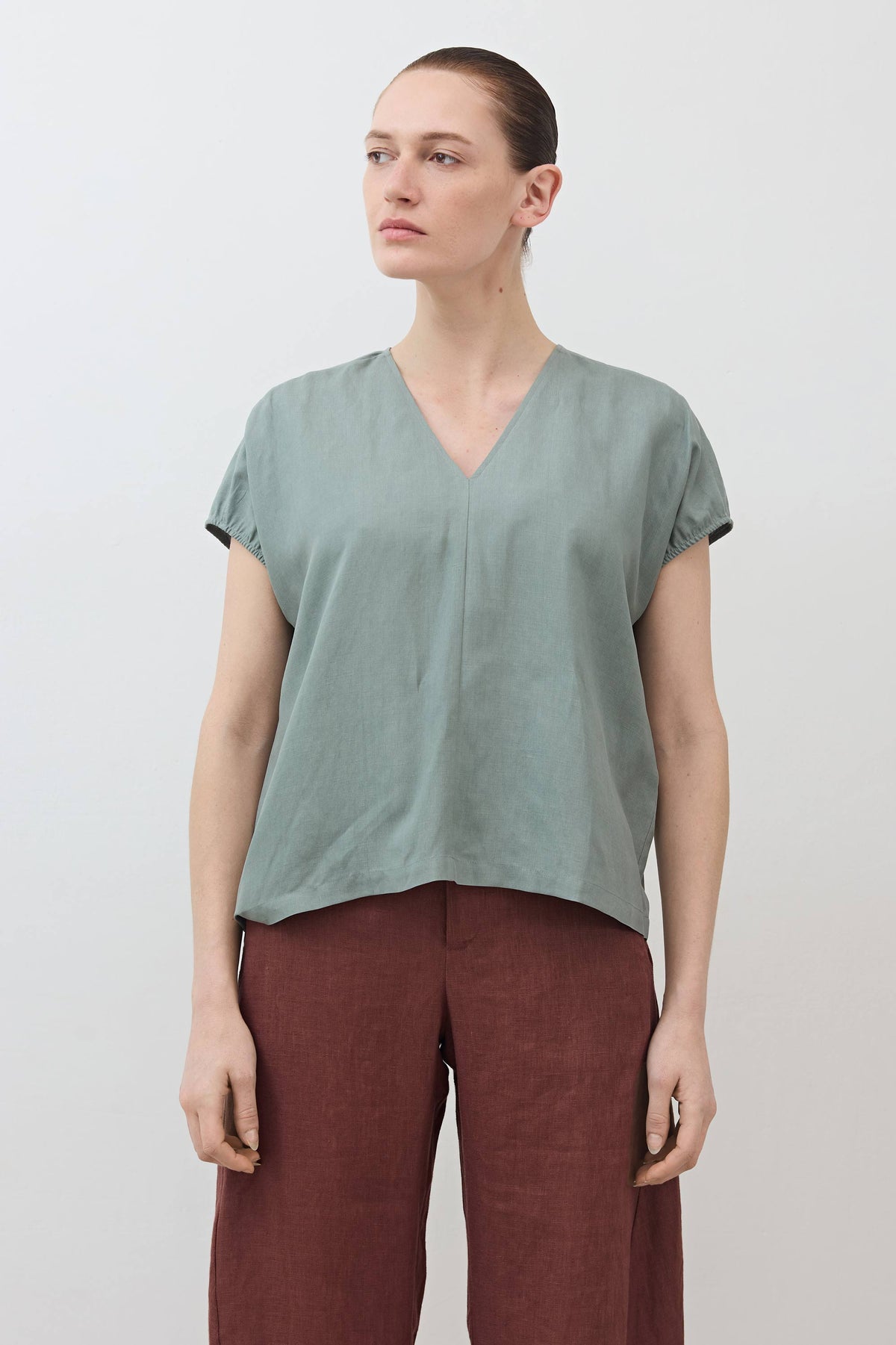 Muted green V-neck silk-linen top with short sleeves and loose fit.