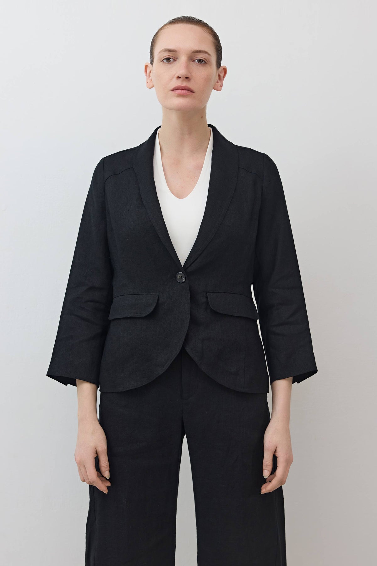 Black cropped blazer front view with notch lapels, single button, and flap pockets