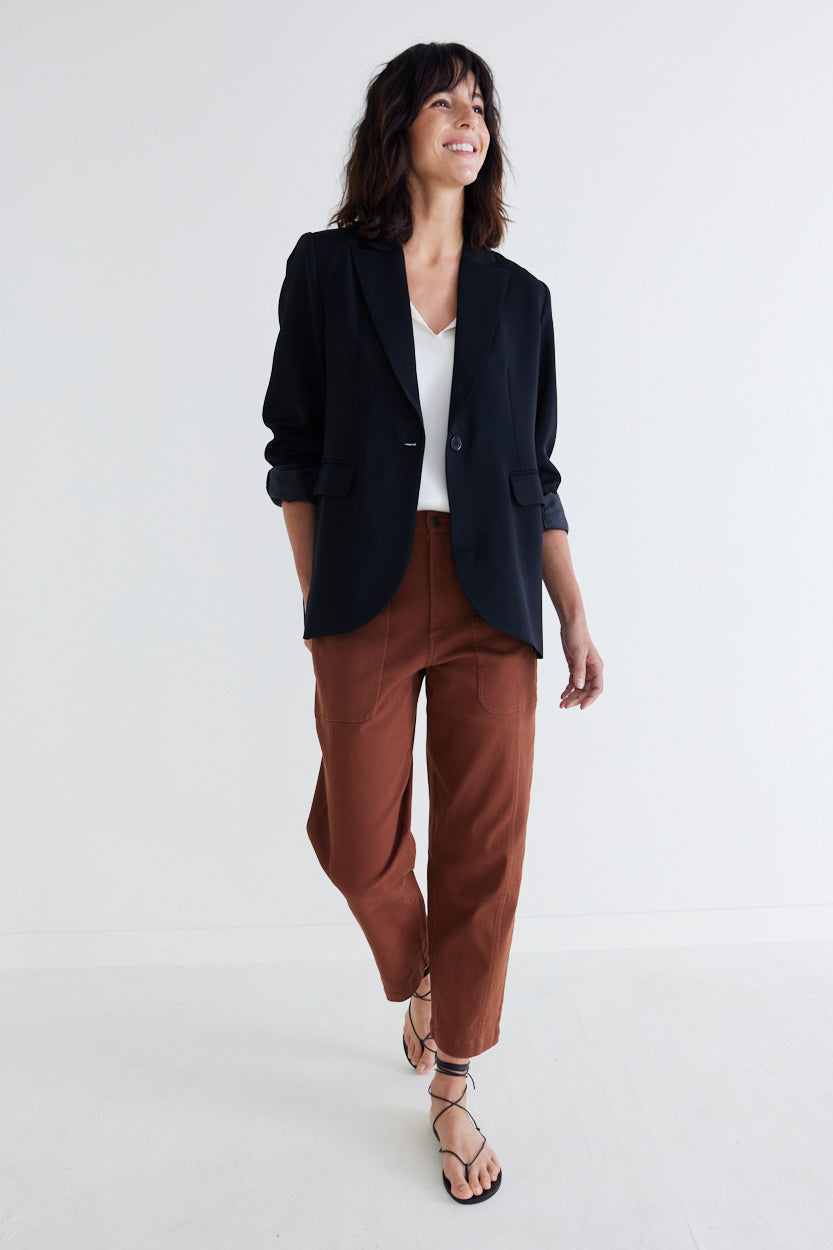 Classic black blazer with notch lapels and single-button front, worn with brown pants