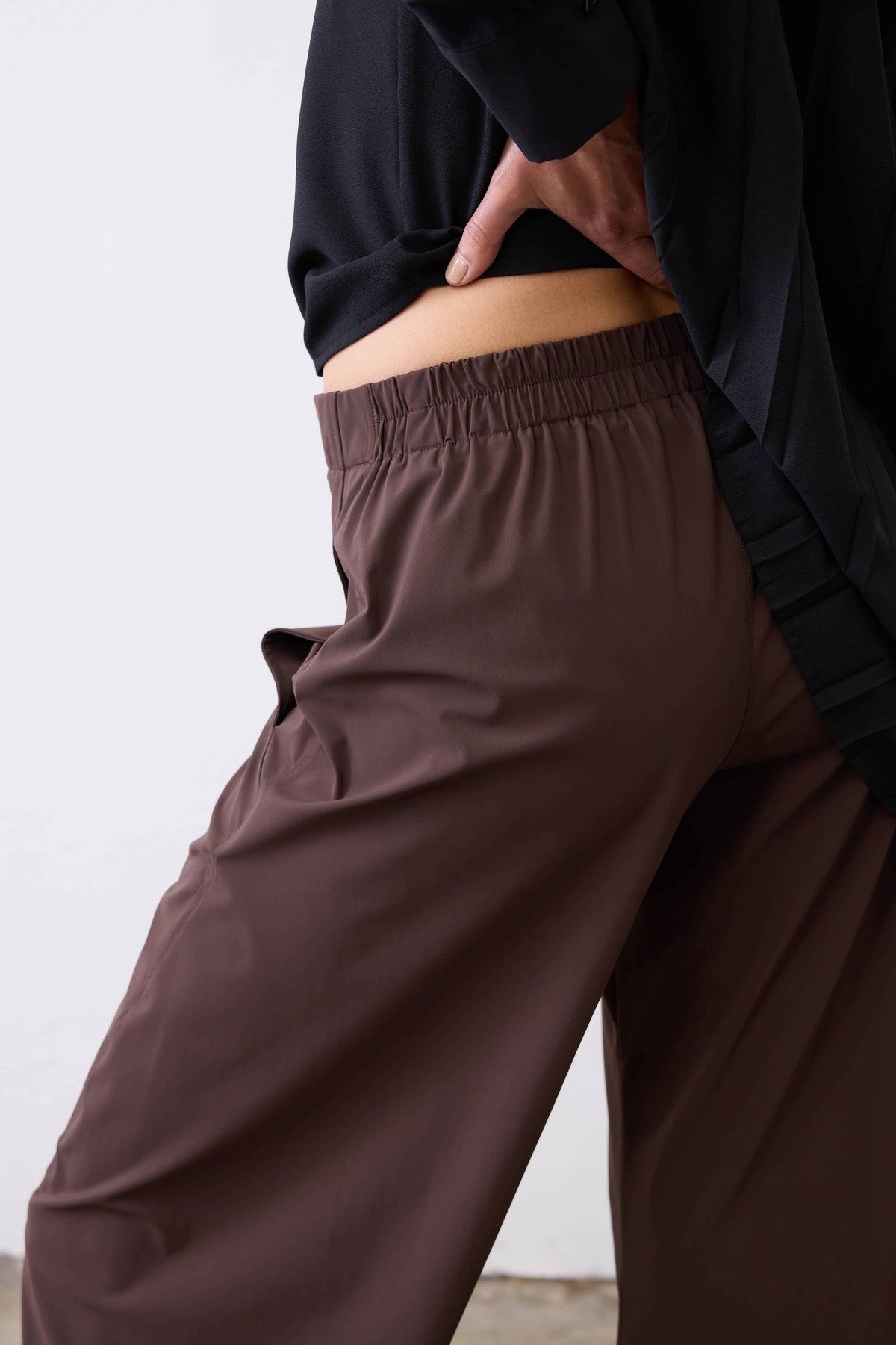 Coffee-brown work pants, elastic waist with loose drape; side pocket detail.