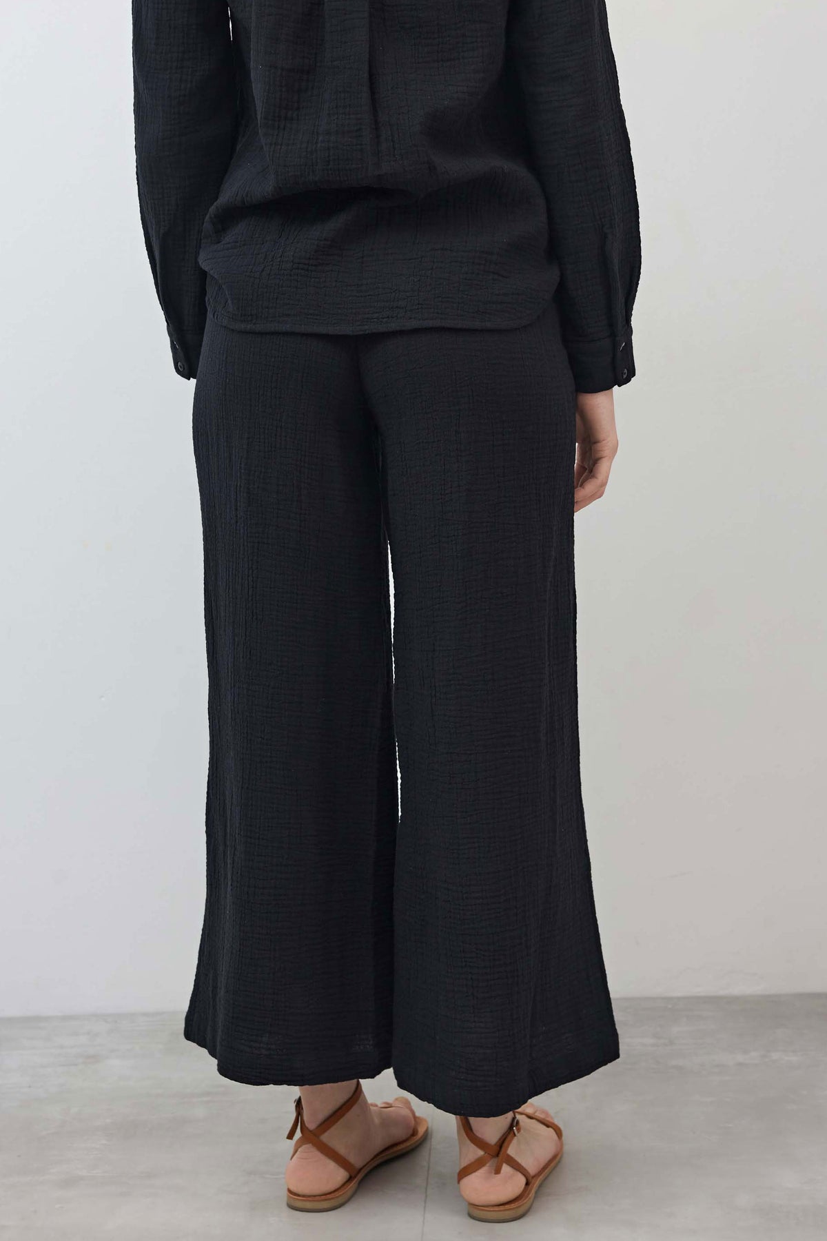 Black airy wide-leg pants with drapey, textured fabric and wide cropped leg openings
