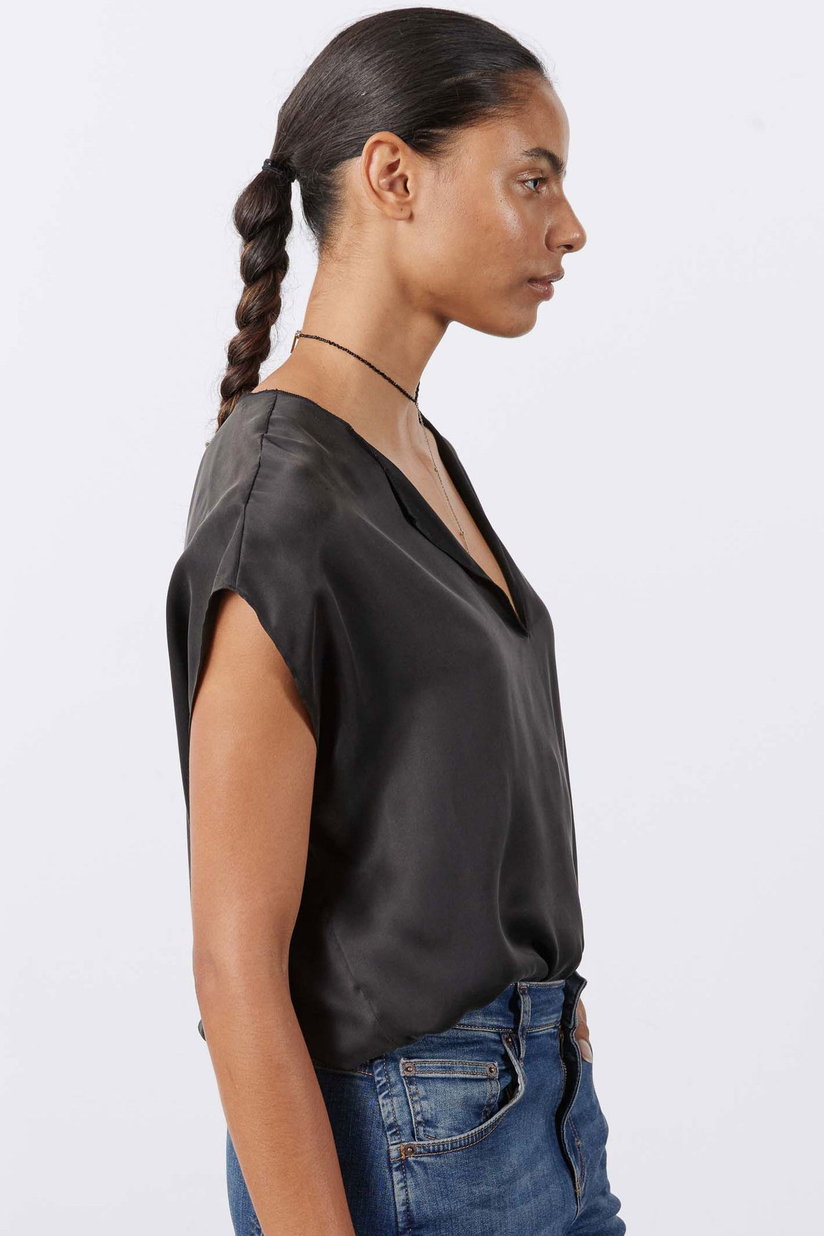 Black silk V-neck top with short sleeves, side view with smooth drape