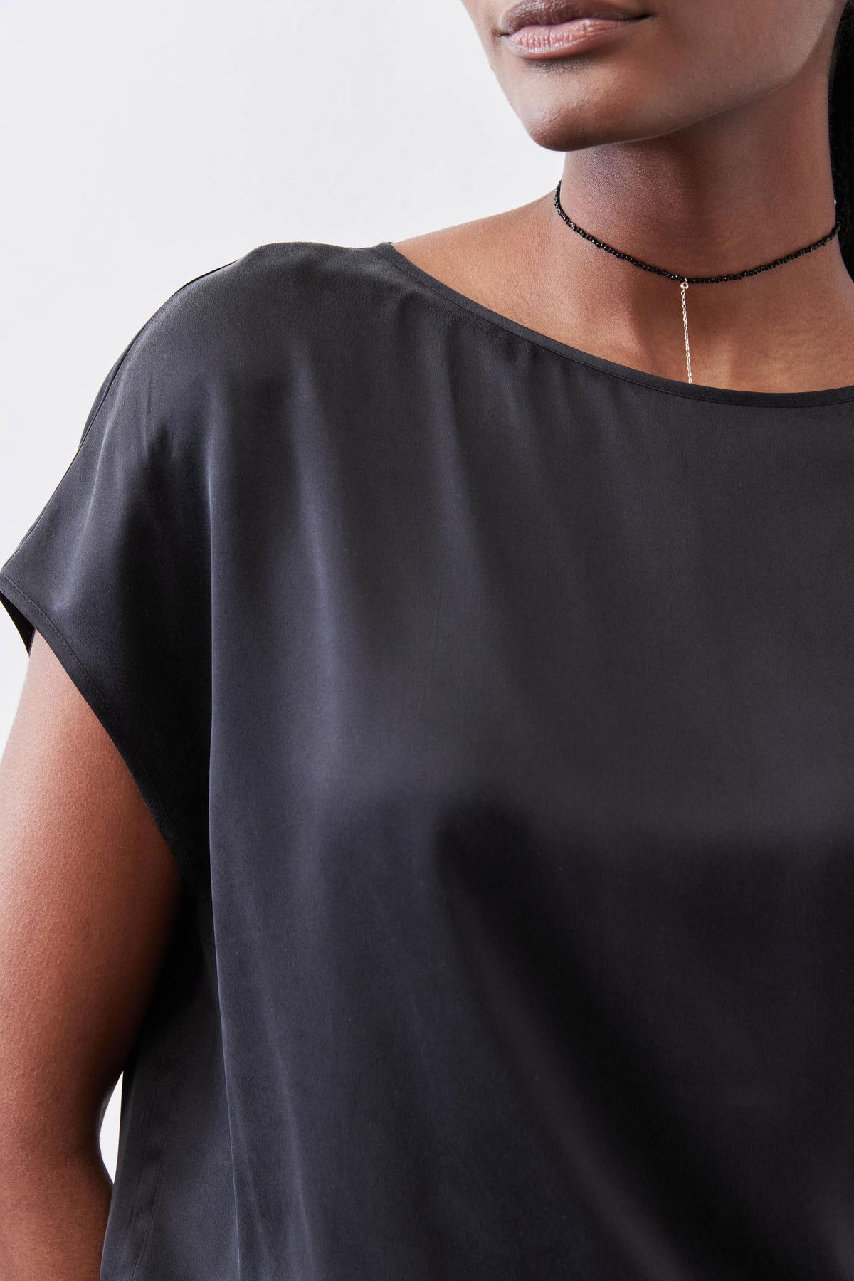 Black silk blouse close-up, smooth drape and wide round neckline