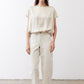 Off-white silk blouse with crew neck and short sleeves, paired with light pants