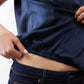 Deep blue silk blouse hem with elastic detail, tucked over dark jeans