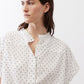 White blouse neckline with small black dots, button placket and foldover collar