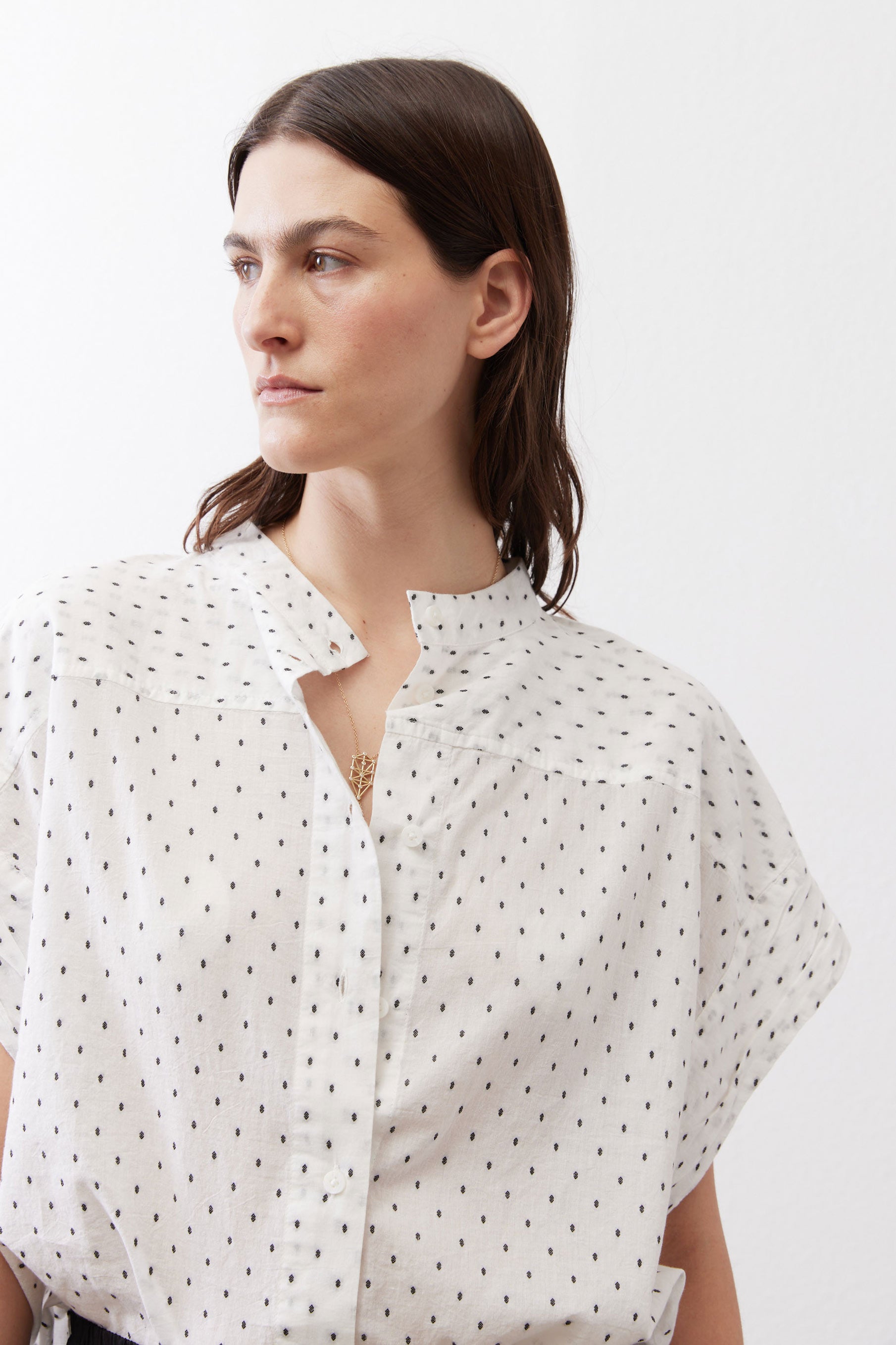 White blouse neckline with small black dots, button placket and foldover collar