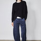 Black asymmetric pullover sweater with crew neck, long sleeves, and diagonal wrap hem