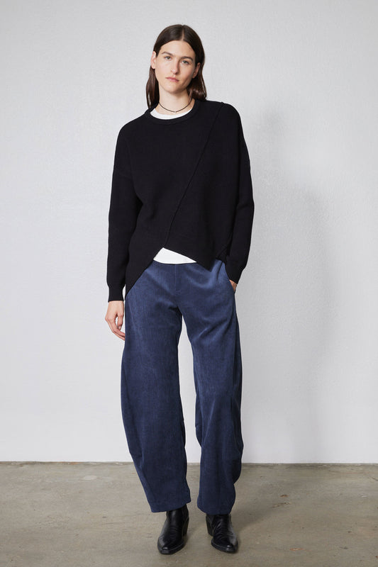 Black asymmetric pullover sweater with crew neck, long sleeves, and diagonal wrap hem