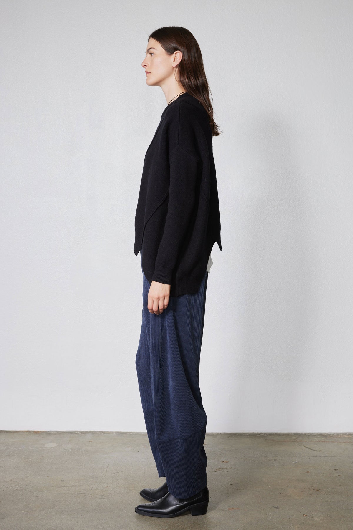 Black asymmetric pullover sweater side profile with diagonal wrap hem and crew neckline