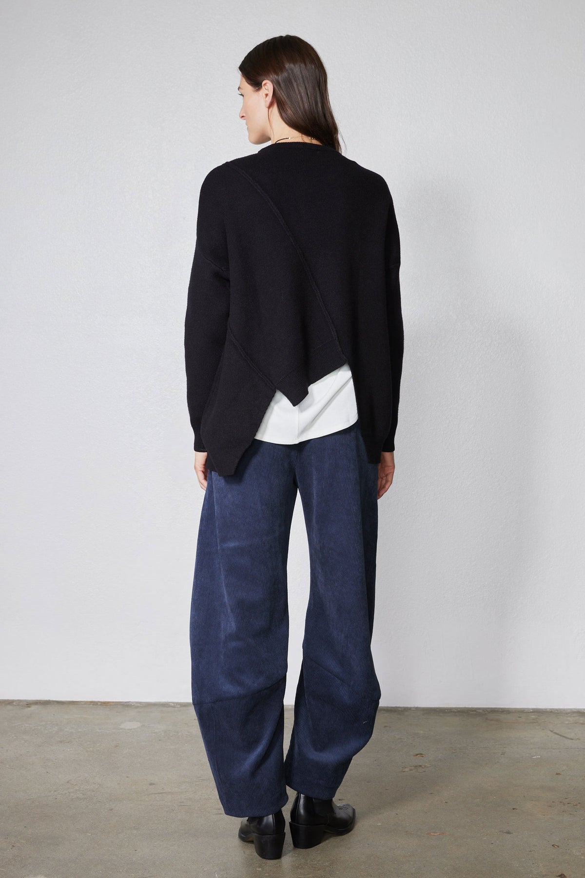 Black asymmetric pullover sweater back drape with diagonal seam and white layered hem