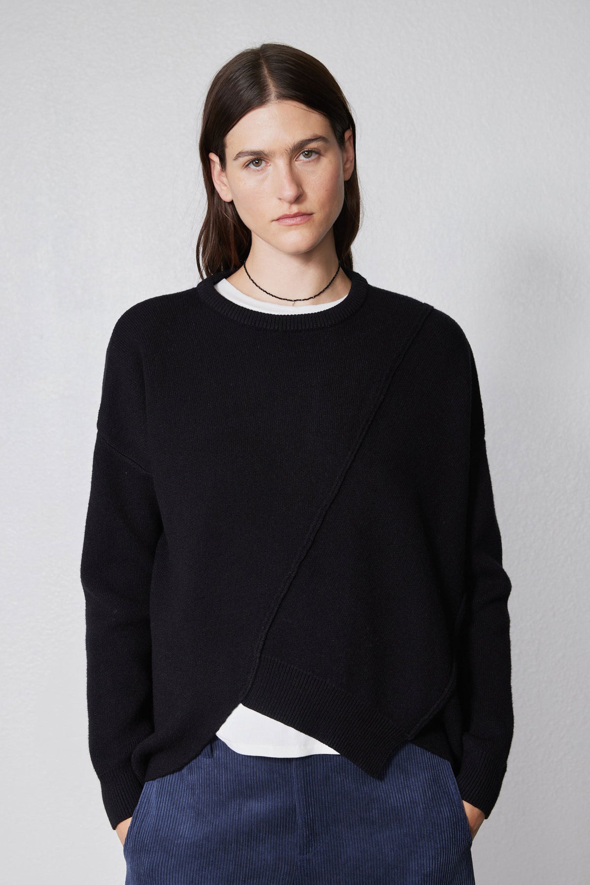 Black asymmetric pullover sweater with ribbed crew neck trim and overlapping diagonal front