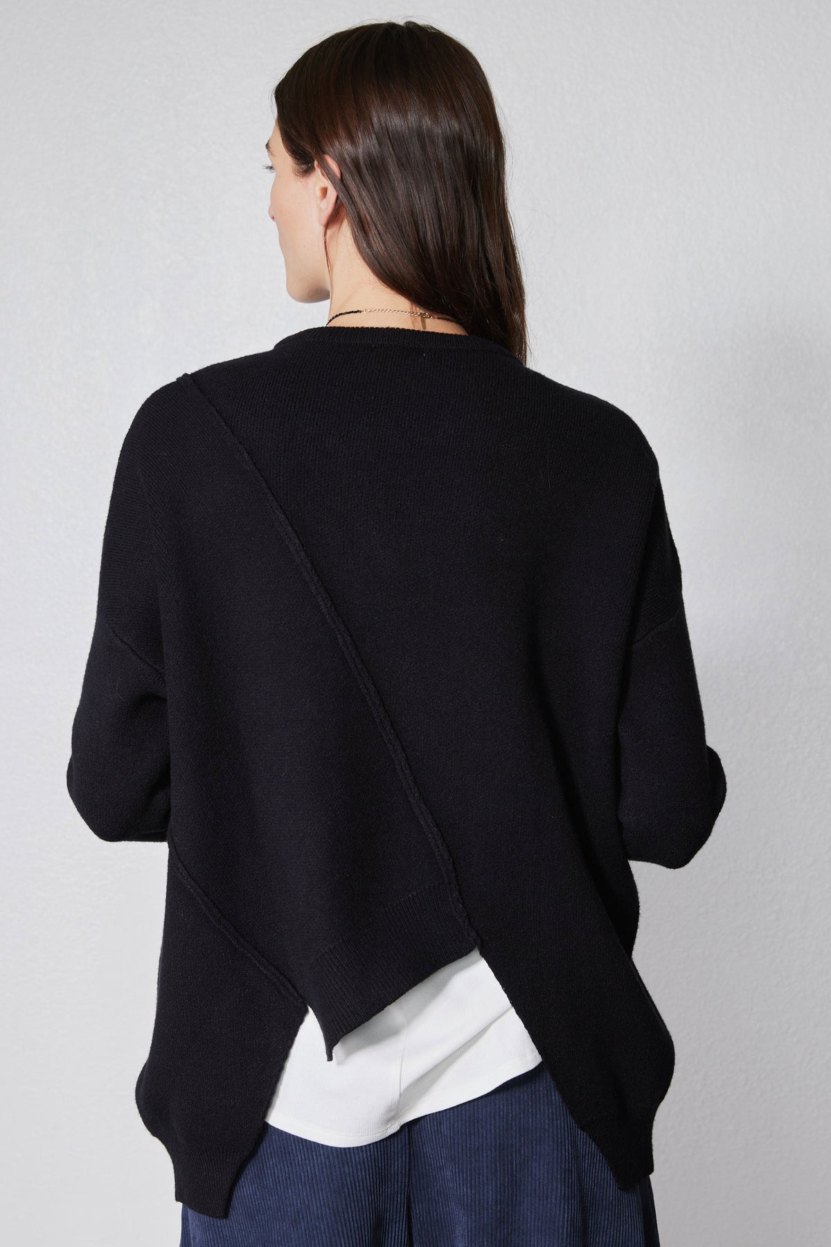 Black asymmetric pullover sweater back with diagonal drape and white layered underhem
