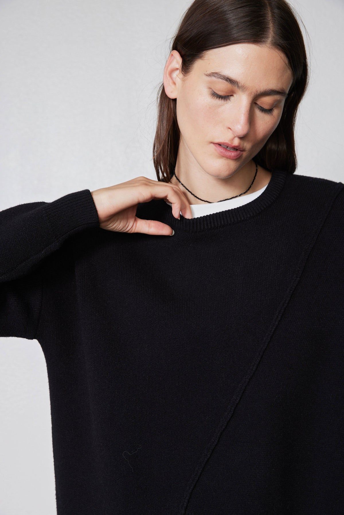 Black asymmetric pullover sweater with ribbed crew neck and diagonal front seam