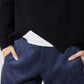 Black sweater hem overlapping white underlayer above blue trousers
