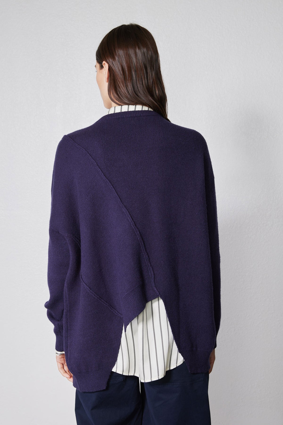 Asymmetric pullover sweater in deep purple, back view with diagonal seam and ribbed cuffs