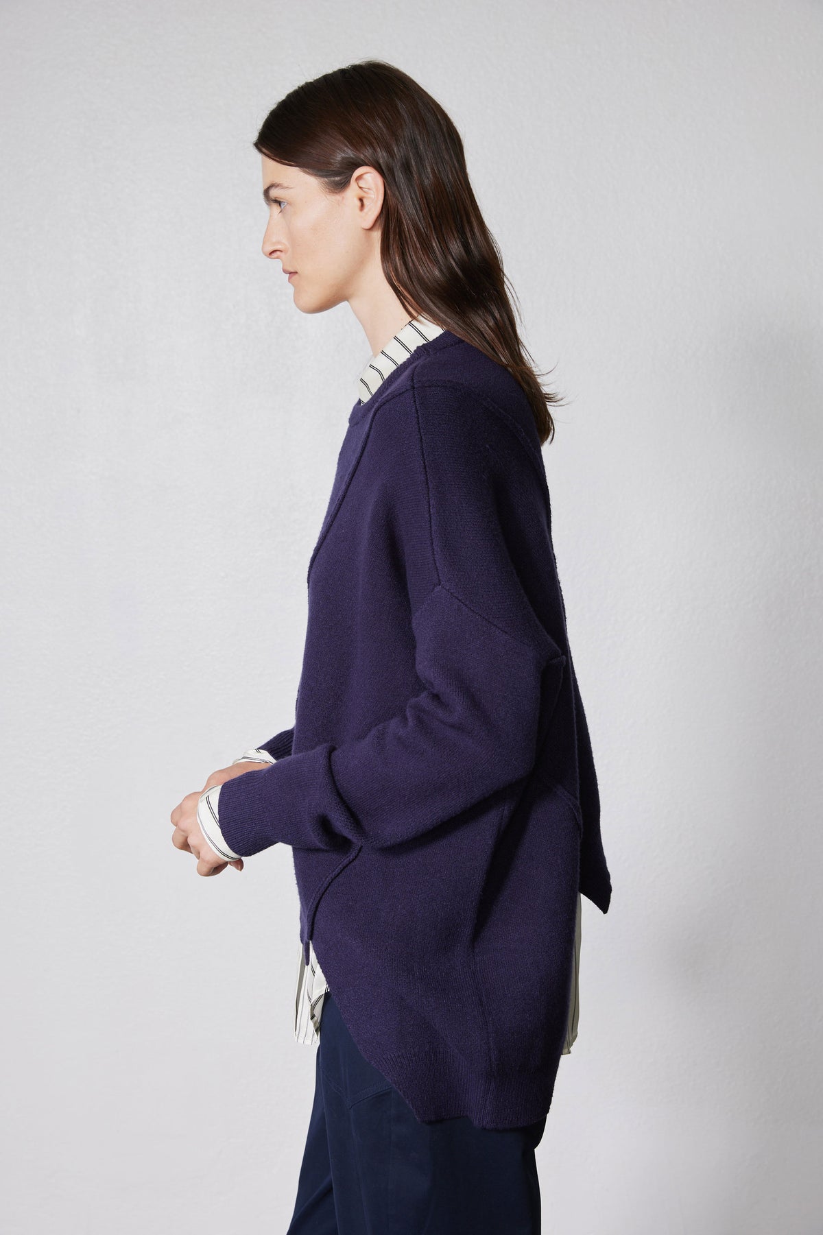 Asymmetric pullover sweater in deep purple, side view with diagonal panel and ribbed cuffs
