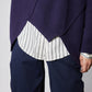 Asymmetric pullover sweater deep purple with diagonal hem opening over a striped shirt
