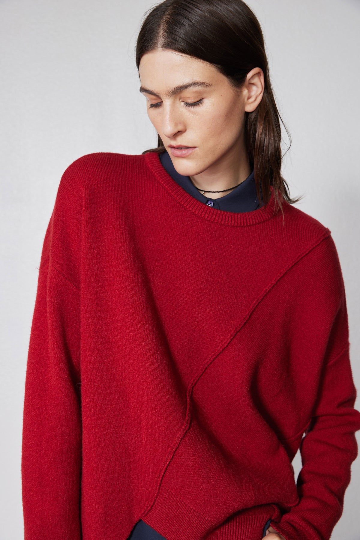Red asymmetric pullover sweater close-up with crew neck ribbing and diagonal seam
