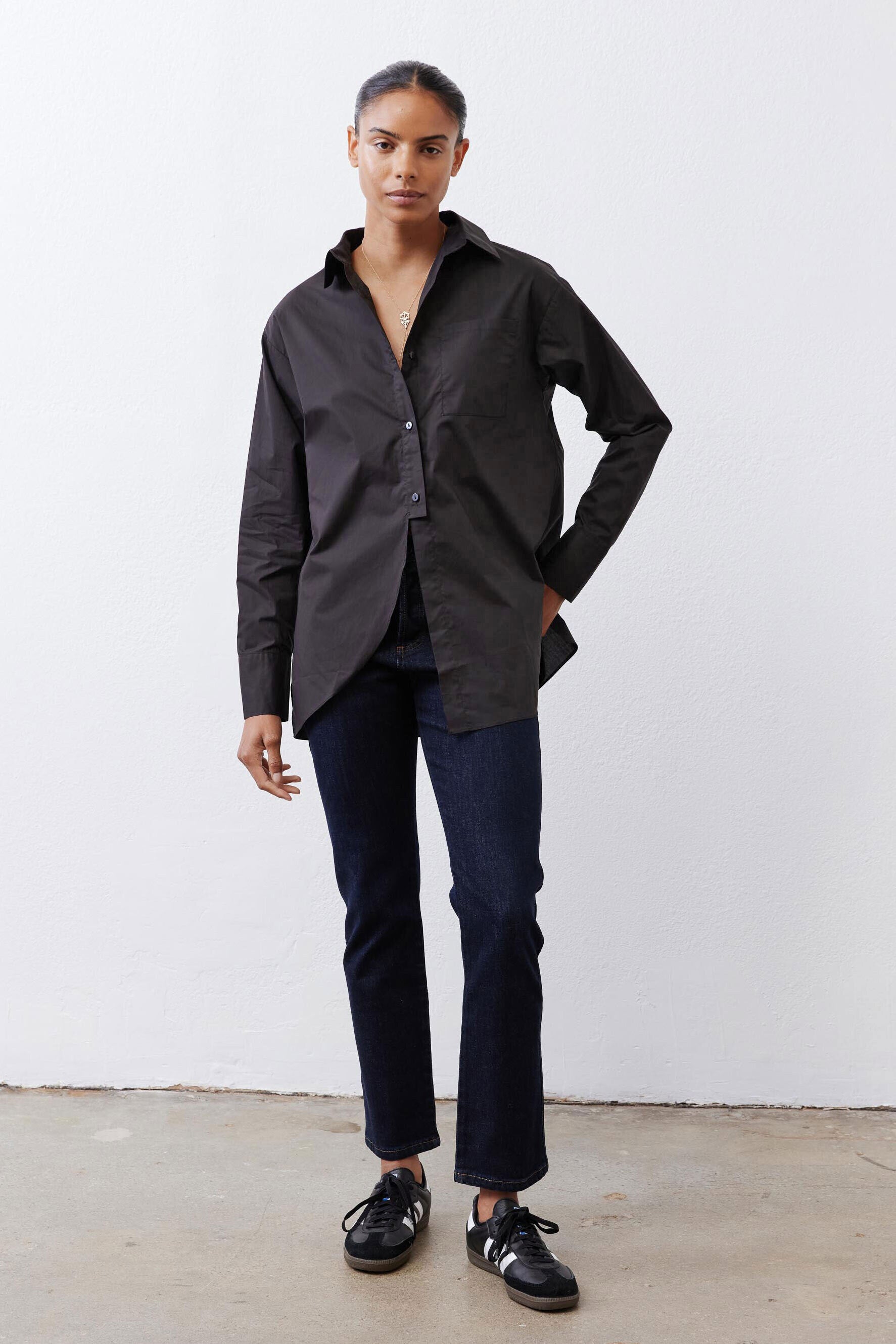 Black asymmetric button-down shirt with long sleeves and curved hem