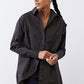 Black asymmetric button-down shirt detail: collar and front button placket