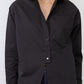 Black asymmetric button-down shirt close-up with collar and chest pocket