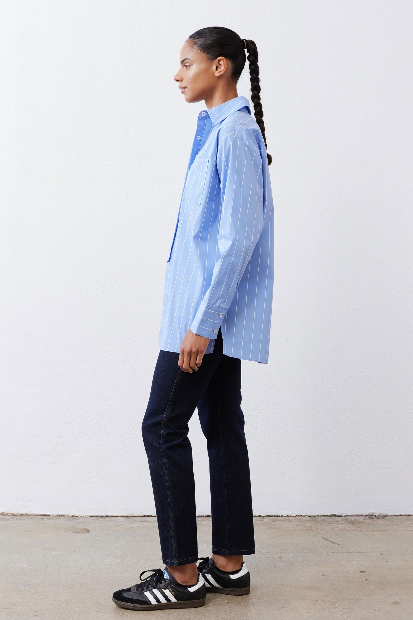 Side view of light blue and white striped button-down shirt, asymmetric hem
