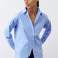 Light blue and white striped button-down shirt with front buttons and asymmetric cut