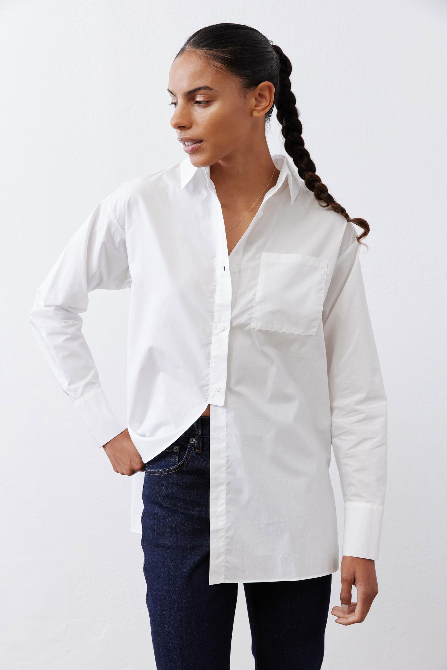 White asymmetric button-down shirt with pointed collar and long sleeves, tucked front