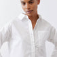 White asymmetric button-down shirt with pointed collar, front buttons and chest pocket