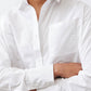 White asymmetric button-down shirt close-up: button placket and long sleeves