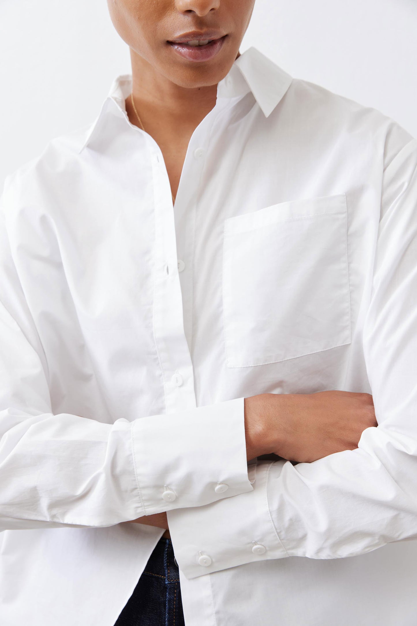 White asymmetric button-down shirt close-up: button placket and long sleeves
