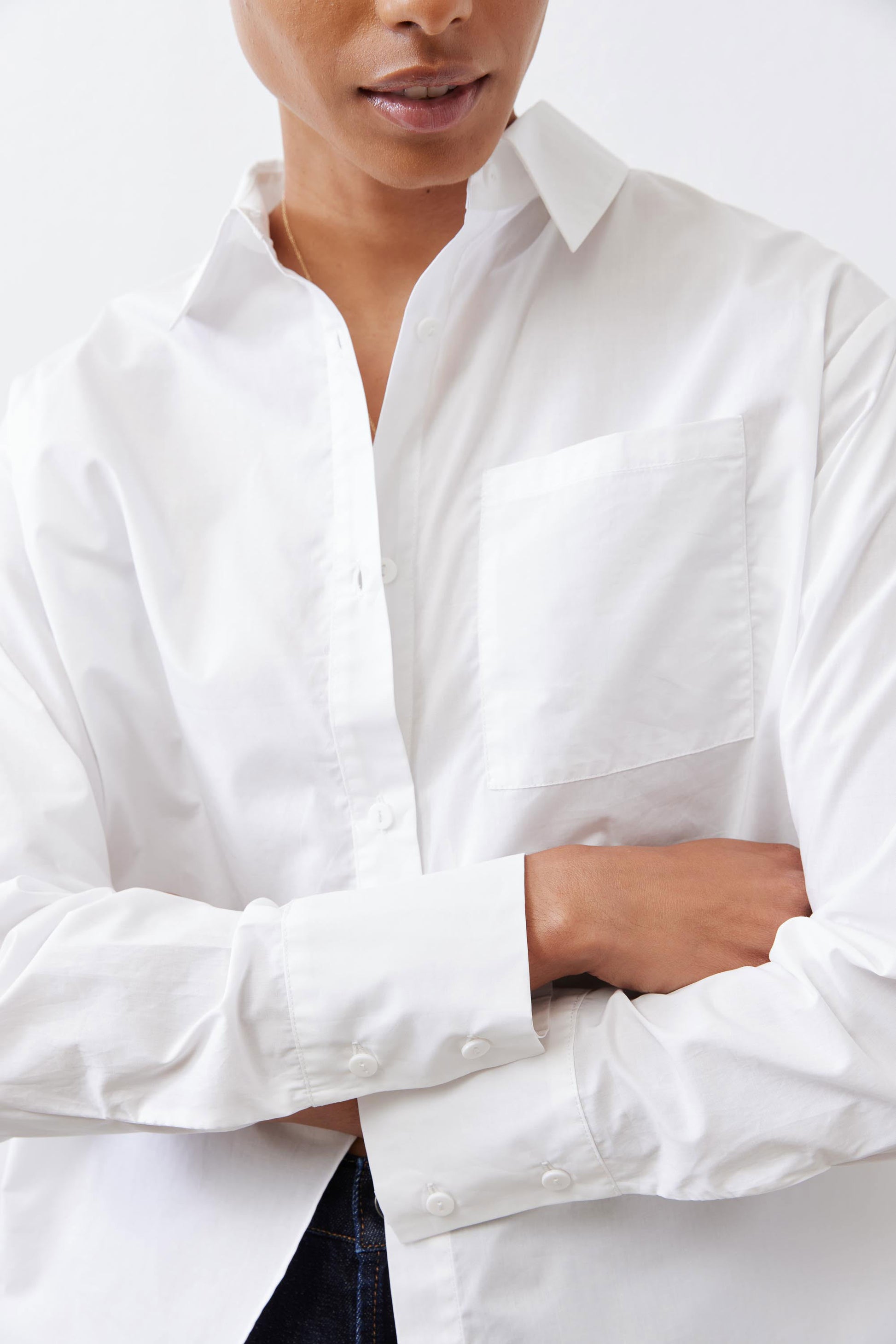 White asymmetric button-down shirt close-up: button placket and long sleeves