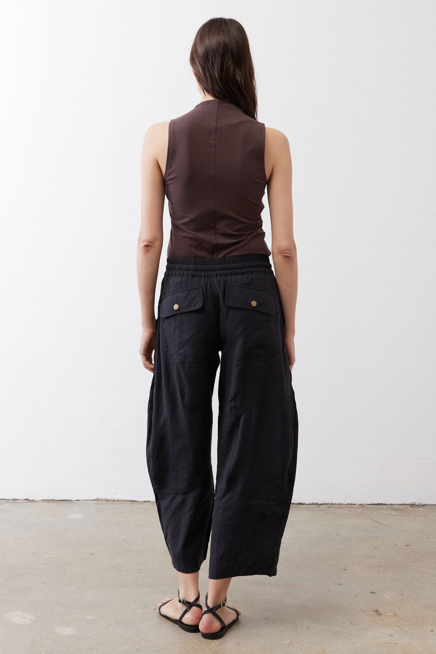 Black baggy utility pants shown from the back with wide cropped legs and elastic waist