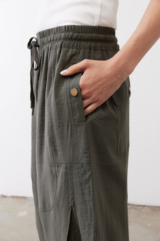 Baggy utility pants in dark olive, close-up of elastic waistband, drawstring, and pocket detail.
