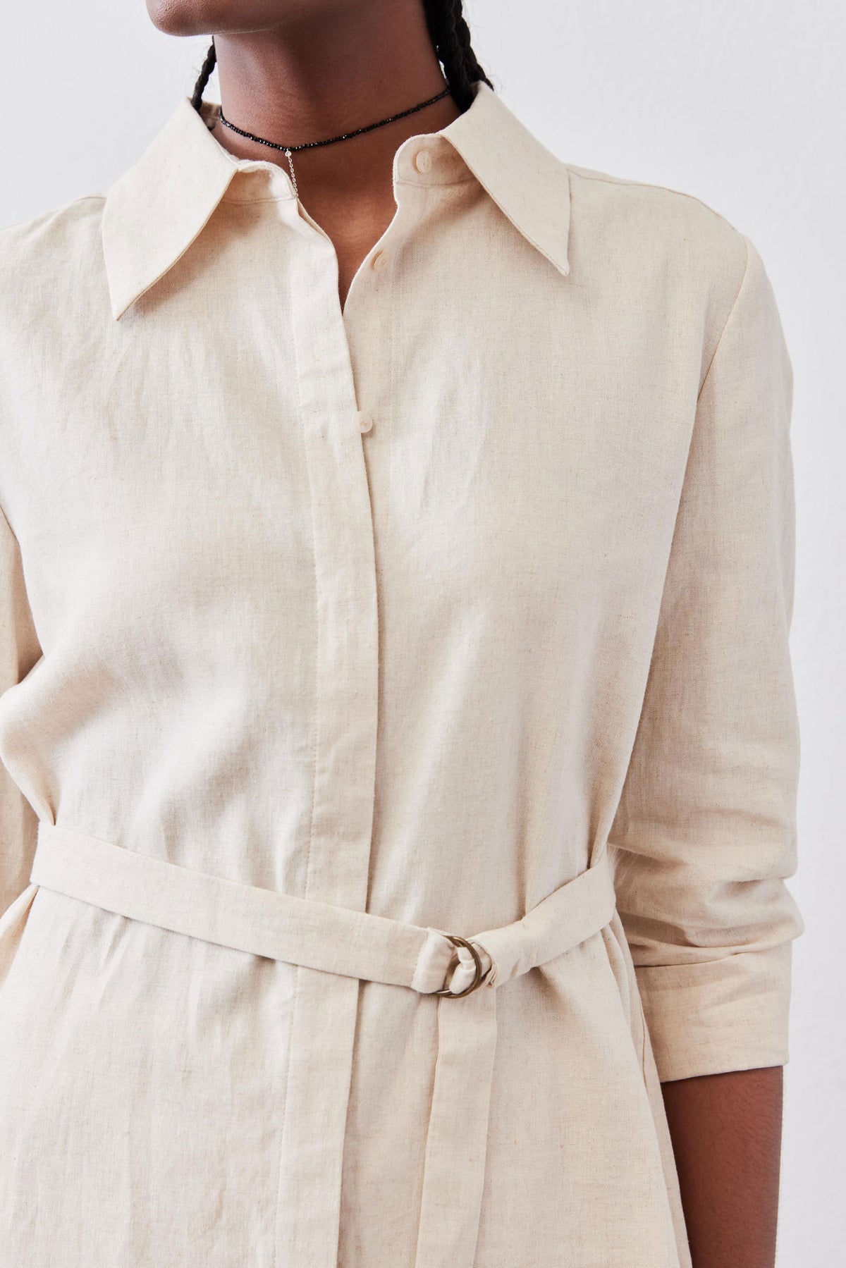 Oat linen tunic close-up: button placket, pointed collar, and tied waist belt.