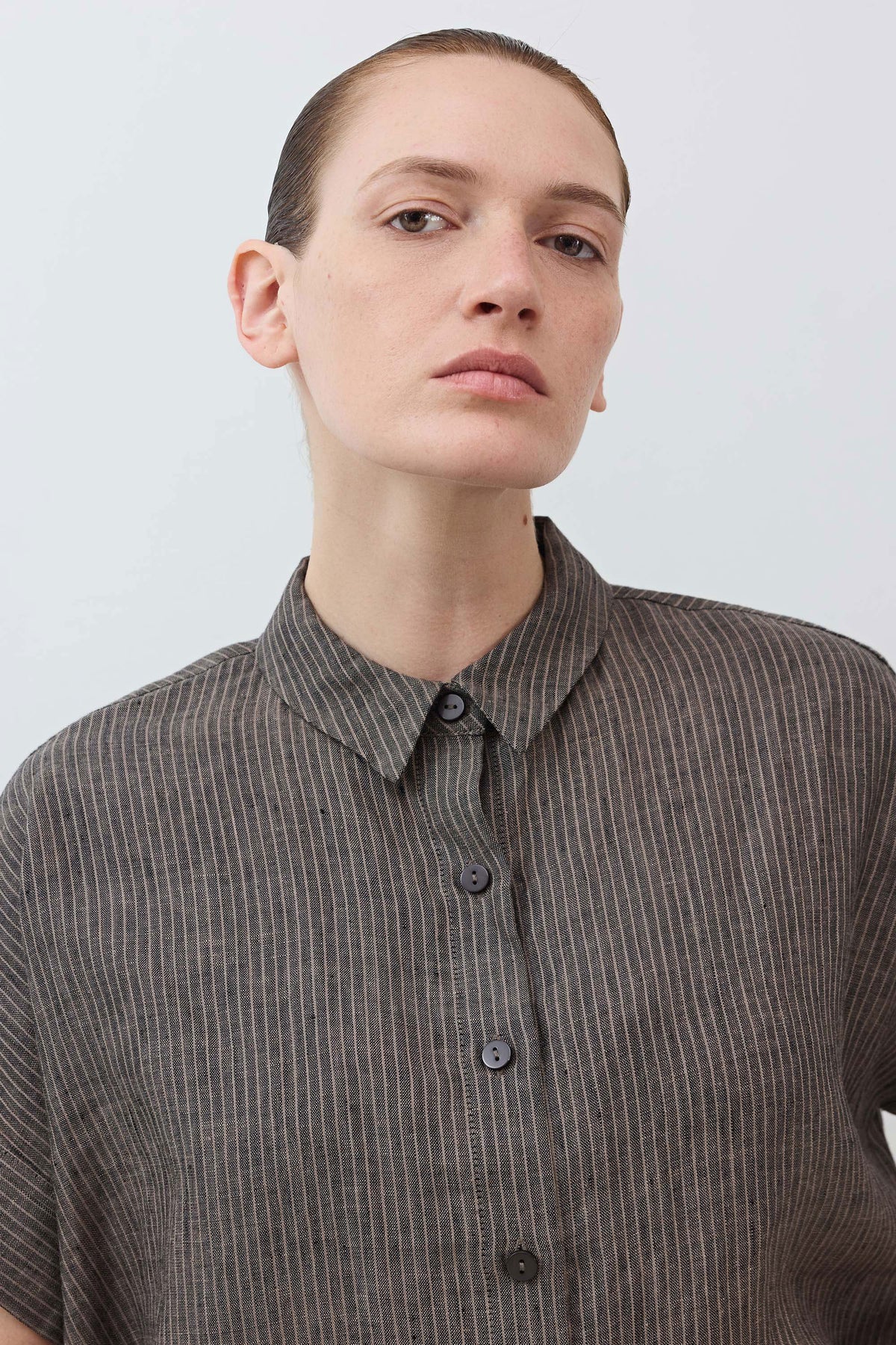 Charcoal linen button-front blouse collar close-up with dark buttons and fine vertical stripes