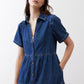 Medium-wash denim midi dress with collared V-neck, short sleeves, and tiered hem