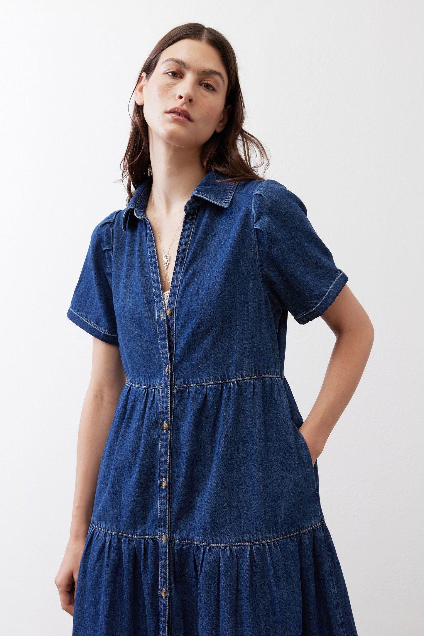 Medium-wash denim midi dress with collared V-neck, short sleeves, and tiered hem