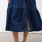 Medium-wash denim midi dress hem with tiered panels and center button detail