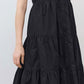Close-up of black tiered poplin dress with button placket and gathered skirt
