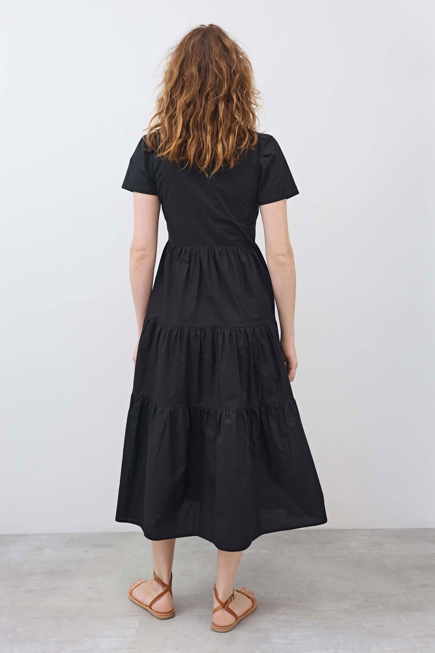 Back view of black long poplin dress with tiered skirt and short sleeves