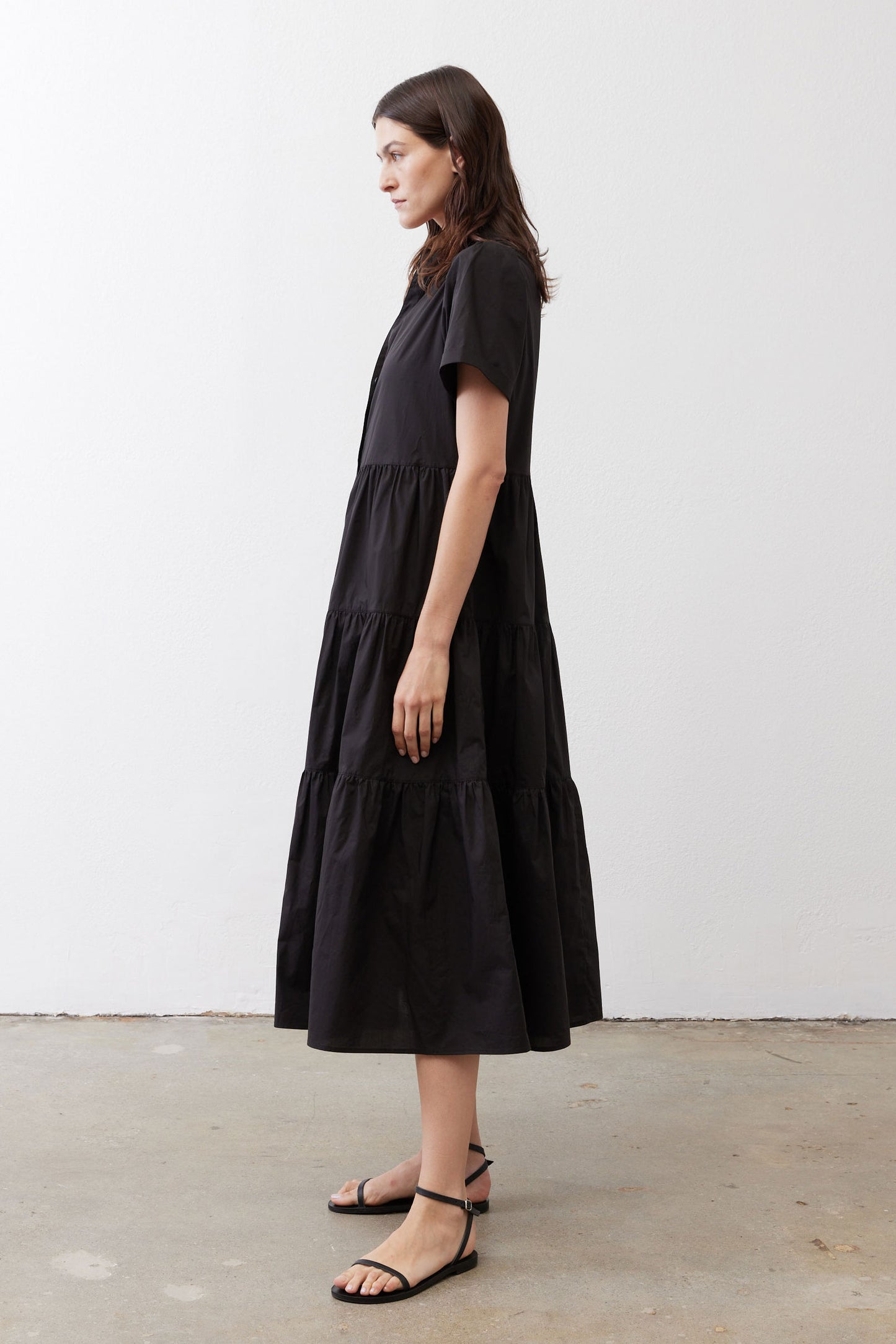 Black long dress from side view with tiered skirt and short sleeves