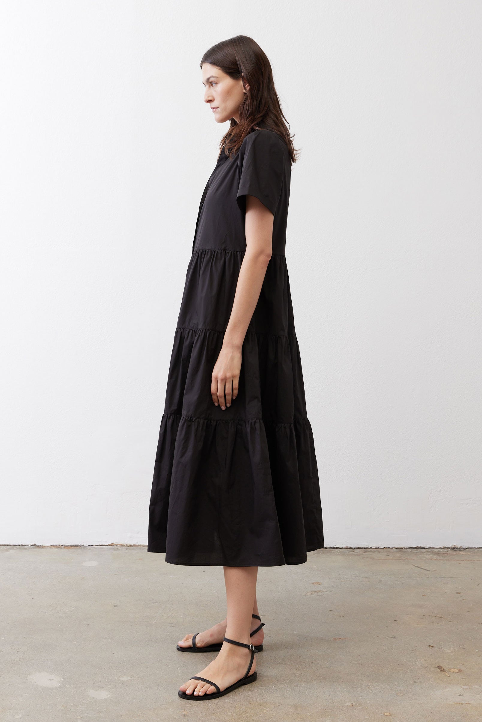 Black long dress from side view with tiered skirt and short sleeves